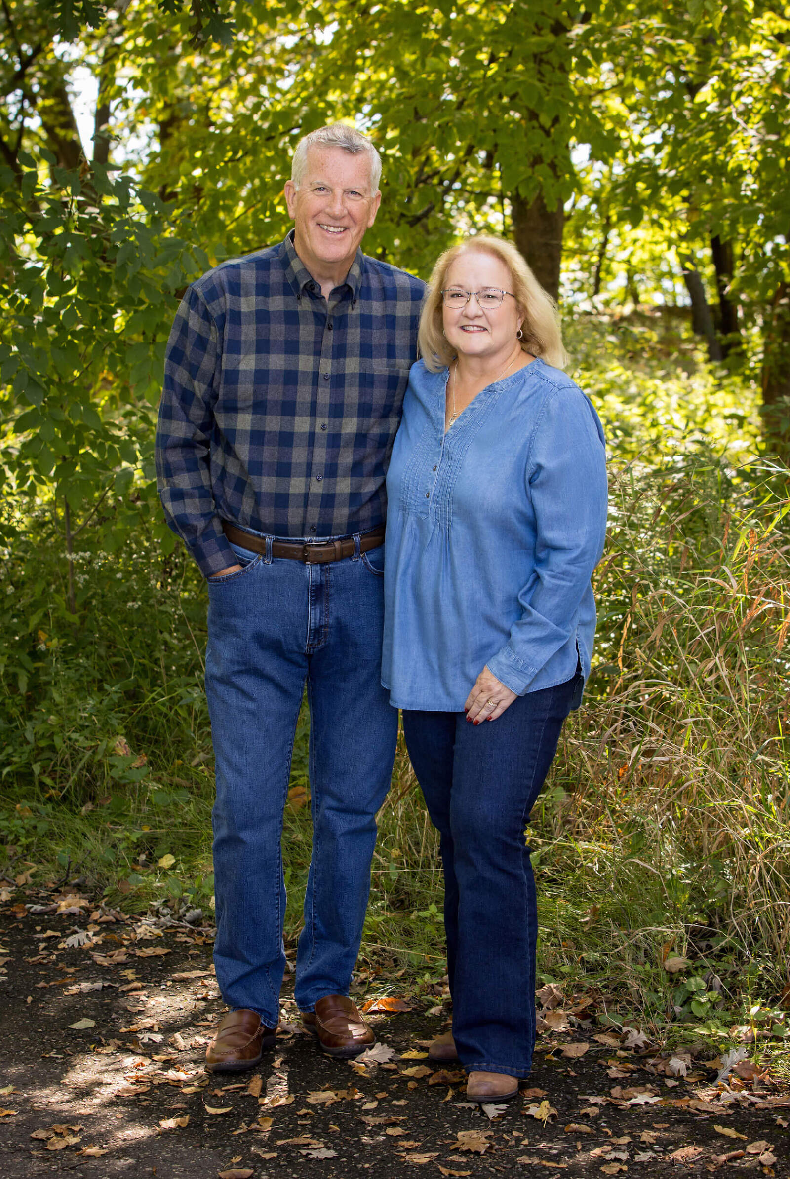 A couple stands together outdoors in a fall family photo shoot with Kristina Lynn Photography and Design