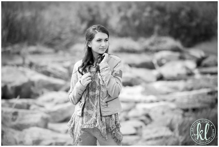 Editorial style black and white image of a girl standing in a rocky river bed.