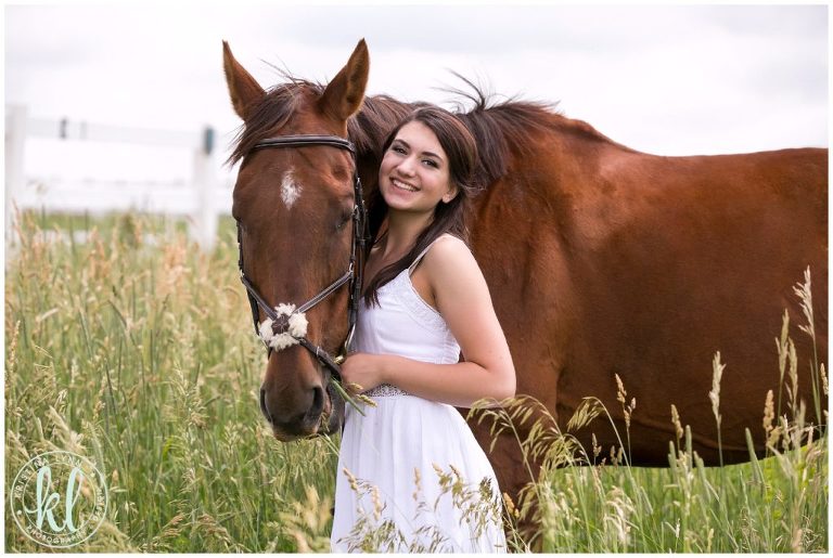 High school senior girl smiling with her horse for her senior photo session.