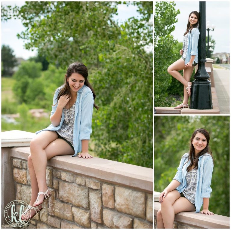 A girl sitting on a rock wall in an urban area.