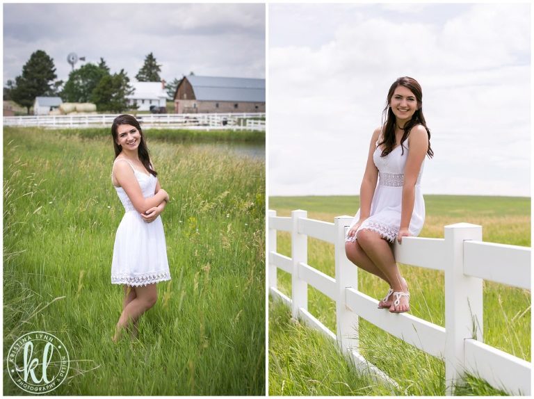 A girl in a white dress sitting on a white picket fence on a farm.