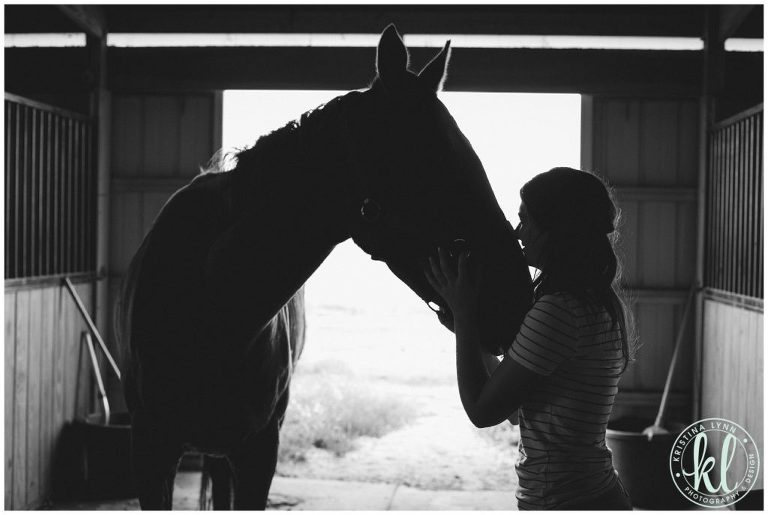 Silhouette photo of a girl kissing her horse in a barn in Parker Colorado.