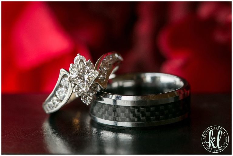 Diamond and titanium wedding bands in front of red flowers.