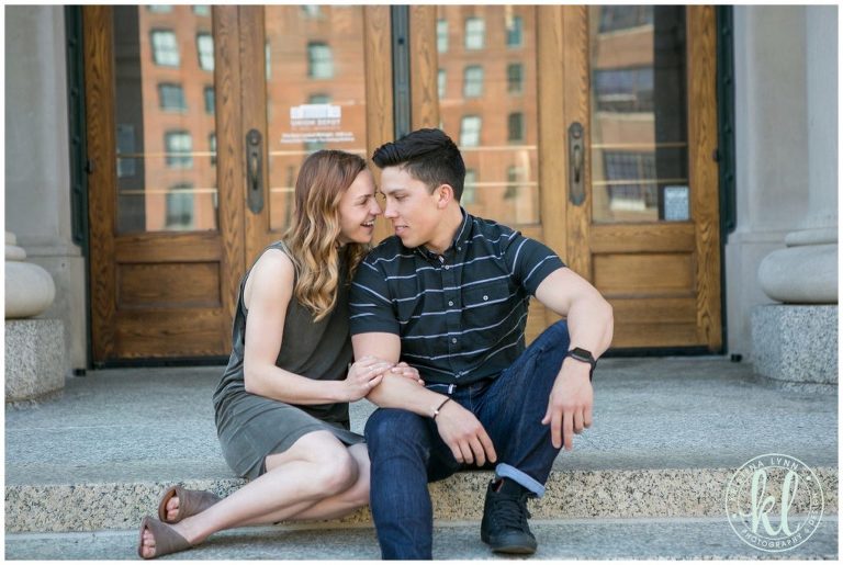 A girl and a guy cuddle together in front of grand wooden doors in downtown St. Paul, Minnesota.