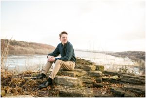 high school boy poses for senior portraits on bluff overlooking st croix river near stillwater minnesota