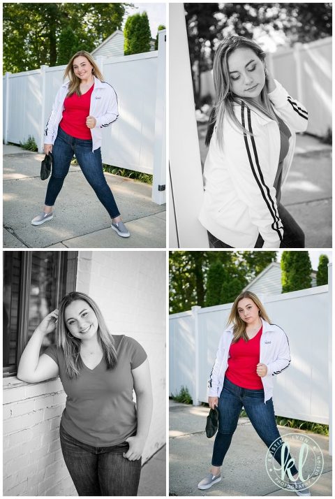 high school senior girl wearing red top and white coat pose for graduation photos in alley