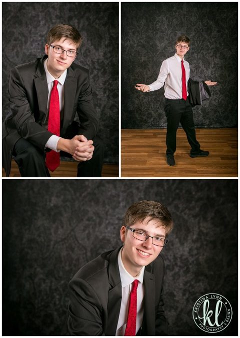 teenage guy wearing black suit and red tie for graduation photos in portrait studio