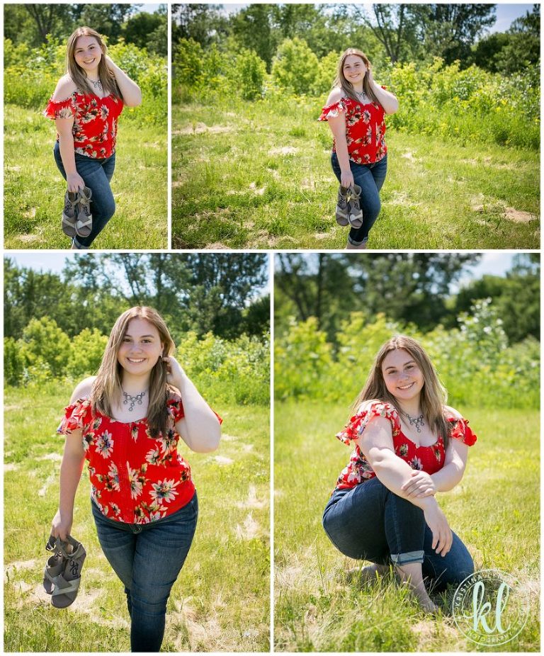 senior girl wearing bright red top from buckle poses for graduation photos in grass