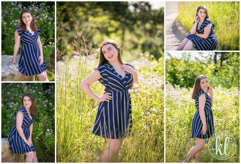 teenage girl in a blue and white striped dress poses for graduation pictures in a field of tall grasses
