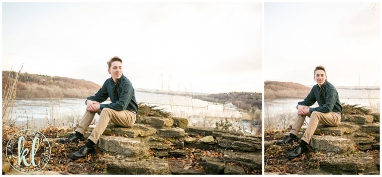 teenage boy sitting on bluff overlooking st croix river for senior portraits