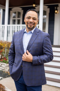 Business man in blue suit outside of a blue house poses for Headshot Photographer Kristina Lynn of KLPD Kristina Lynn Photography & Design