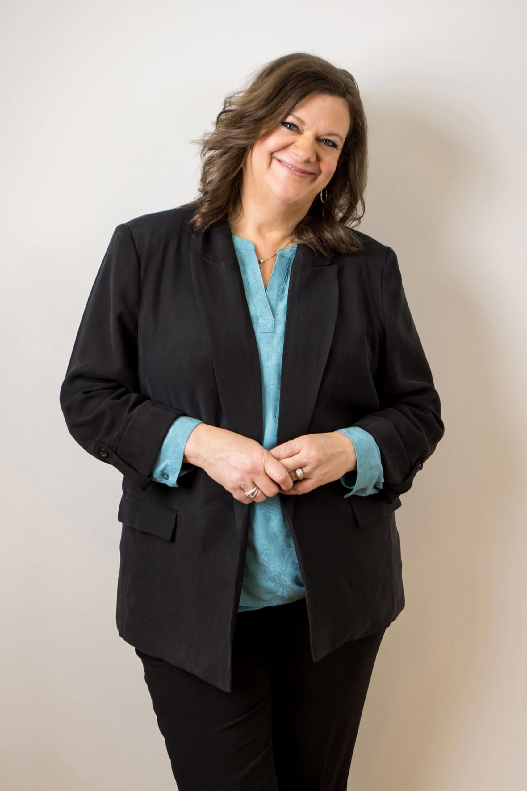Business Headshot of woman with stylish brown hair, a blue blouse and black suit smiles at Kristina Lynn's Camera for her in studio headshots in Minnesota and Iowa