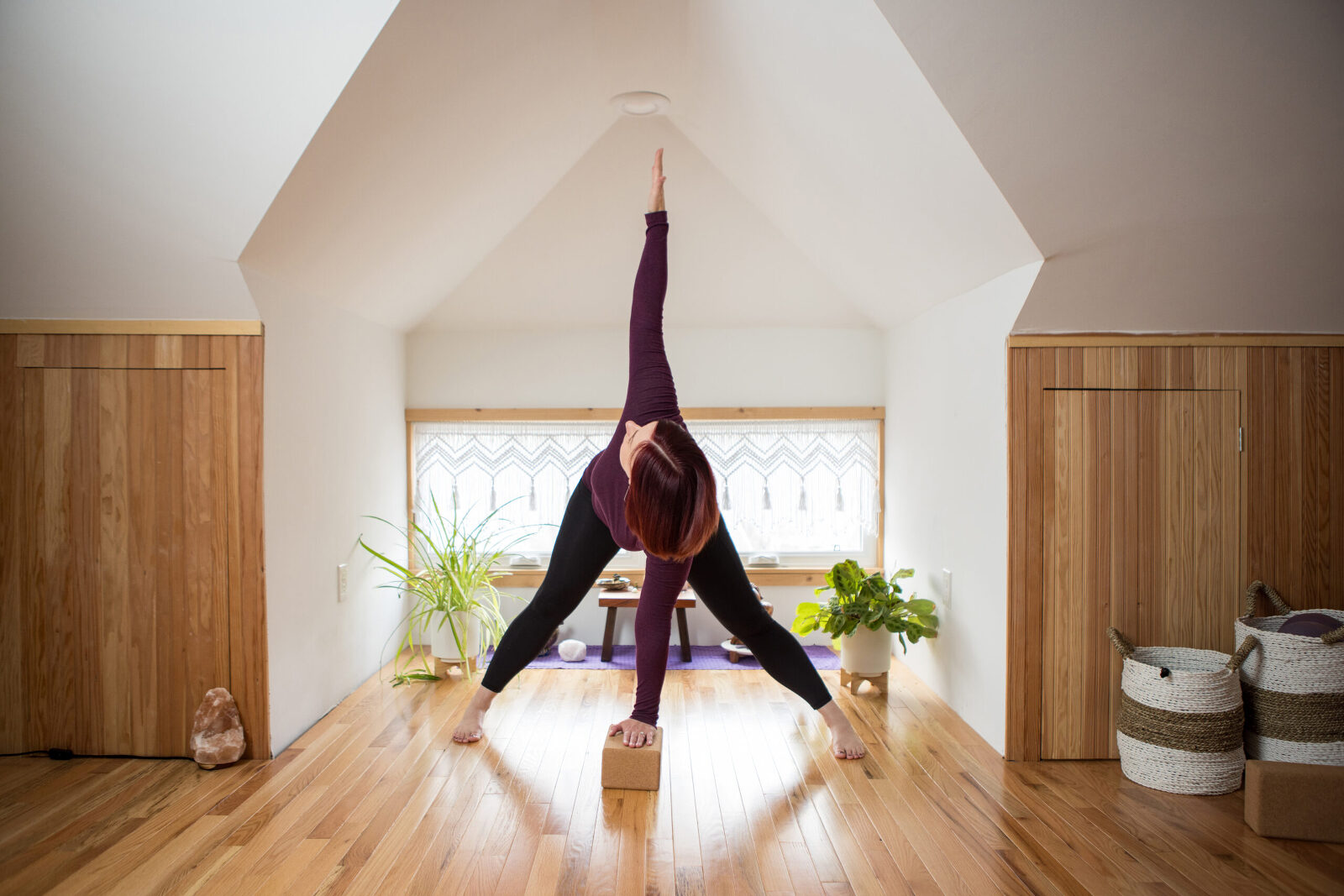 A woman doing a yoga post in the middle of her clean, brightly lit studio